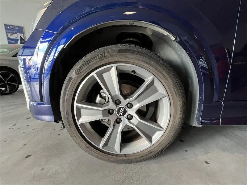 Gros plan sur la roue avant gauche d'un Audi Q2 bleu Navarre métal, mettant en valeur la jante alliage S-Line et le pneu Continental.