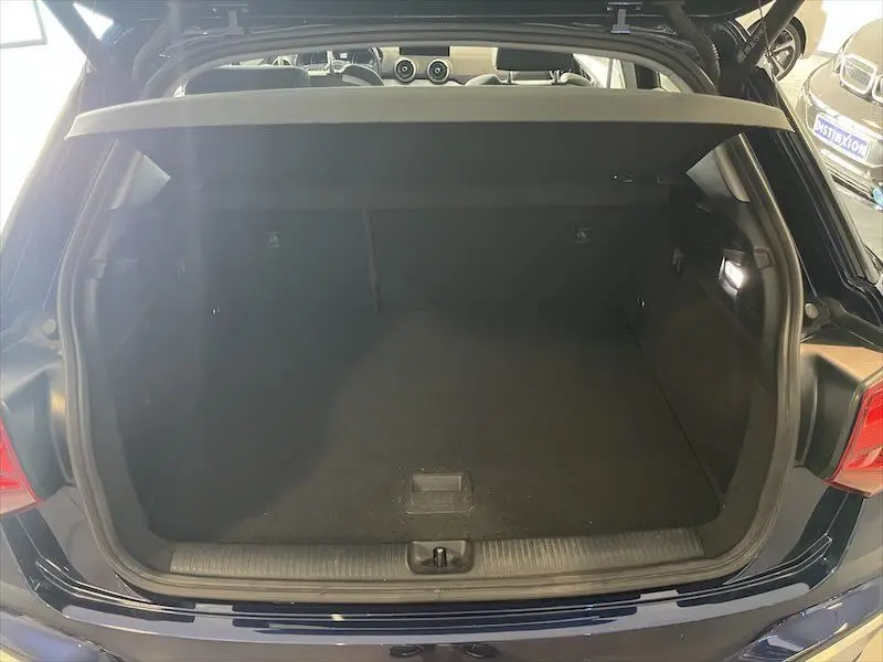 Coffre ouvert vu de l'arrière d'un Audi Q2 bleu Navarre métal 2021, version S-Line avec intérieur sombre.
