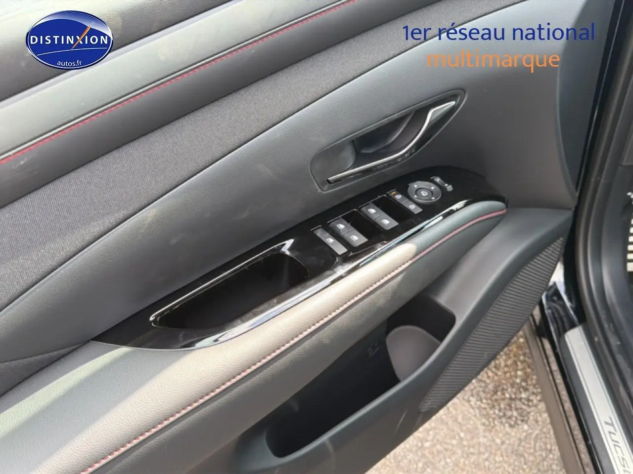 Détail de la porte avant gauche du Hyundai Tucson noir 2026 avec commandes de vitres et poignée intérieure chrome.