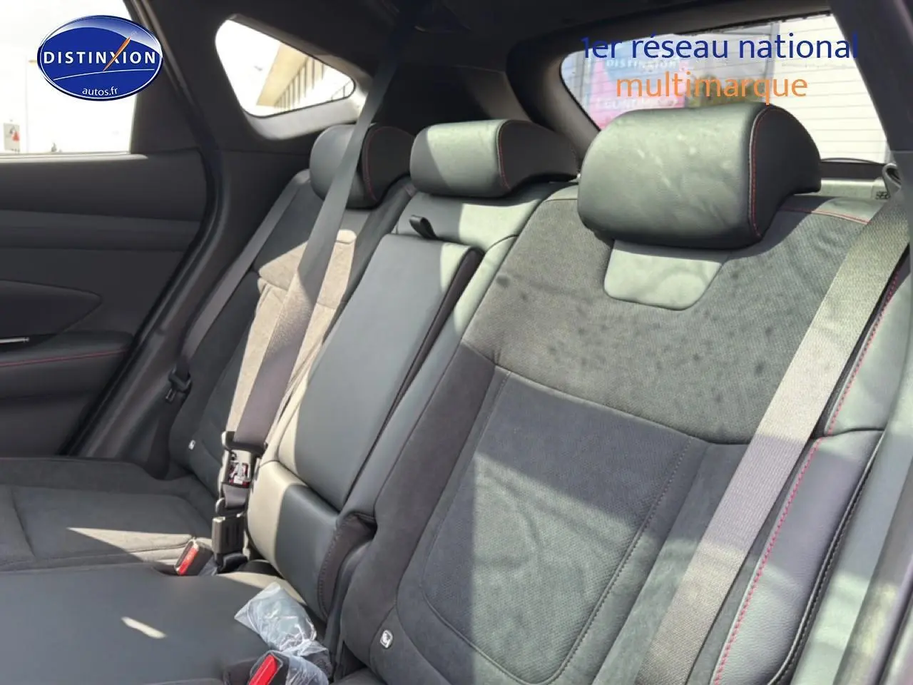 Vue latérale intérieure montrant les sièges arrière en cuir noir et alcantara avec surpiqûres rouges du Hyundai Tucson 2026.