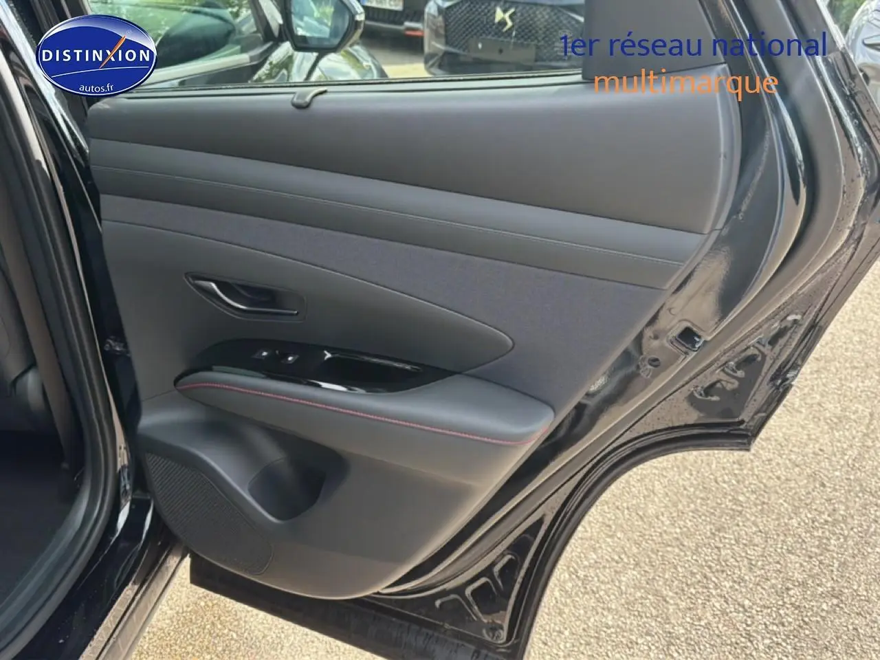 Vue rapprochée de la porte arrière gauche noire du Hyundai Tucson 2026 avec garniture cuir et surpiqûres rouges.
