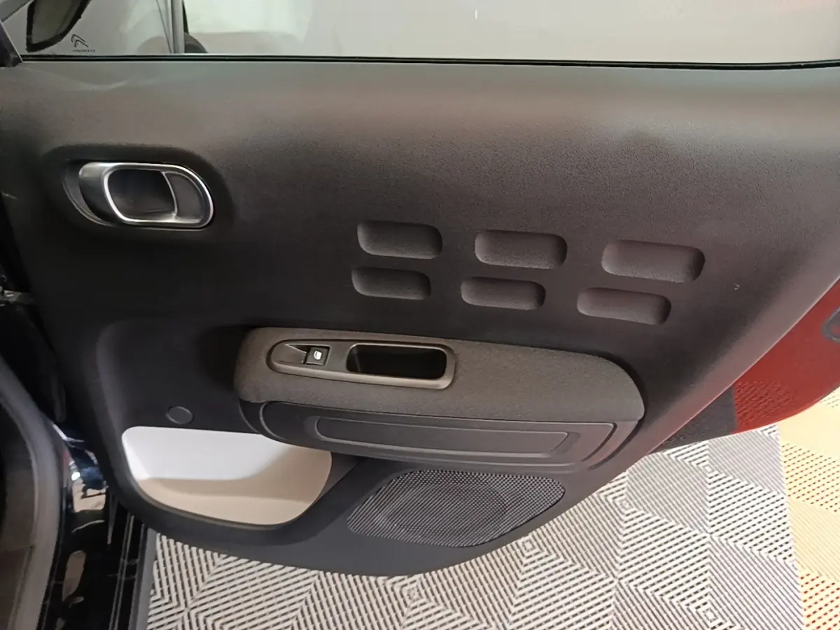 Vue rapprochée de la porte intérieure côté conducteur noire avec insert gris clair et commande de vitre.