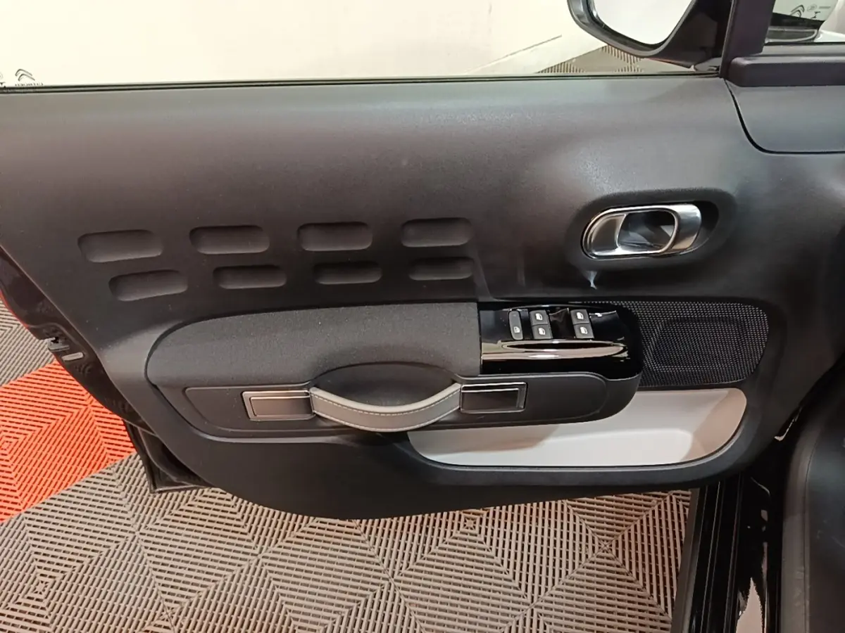 Gros plan sur la porte avant gauche noire de la Citroën C3 2022 avec commandes de vitres et poignée intégrée.