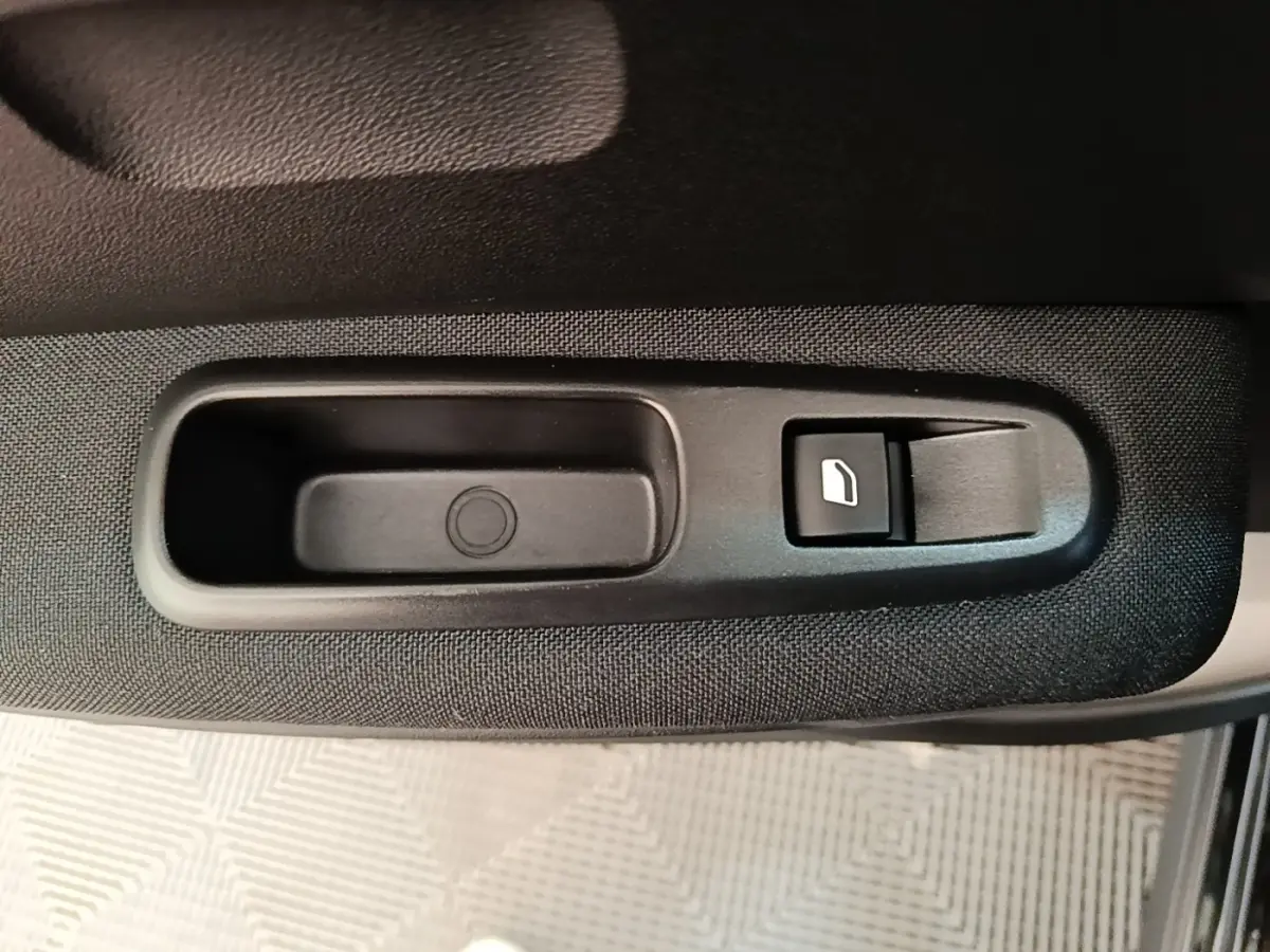Gros plan sur le bouton de commande de la vitre électrique côté conducteur d'une Citroën C3 noire 2022.