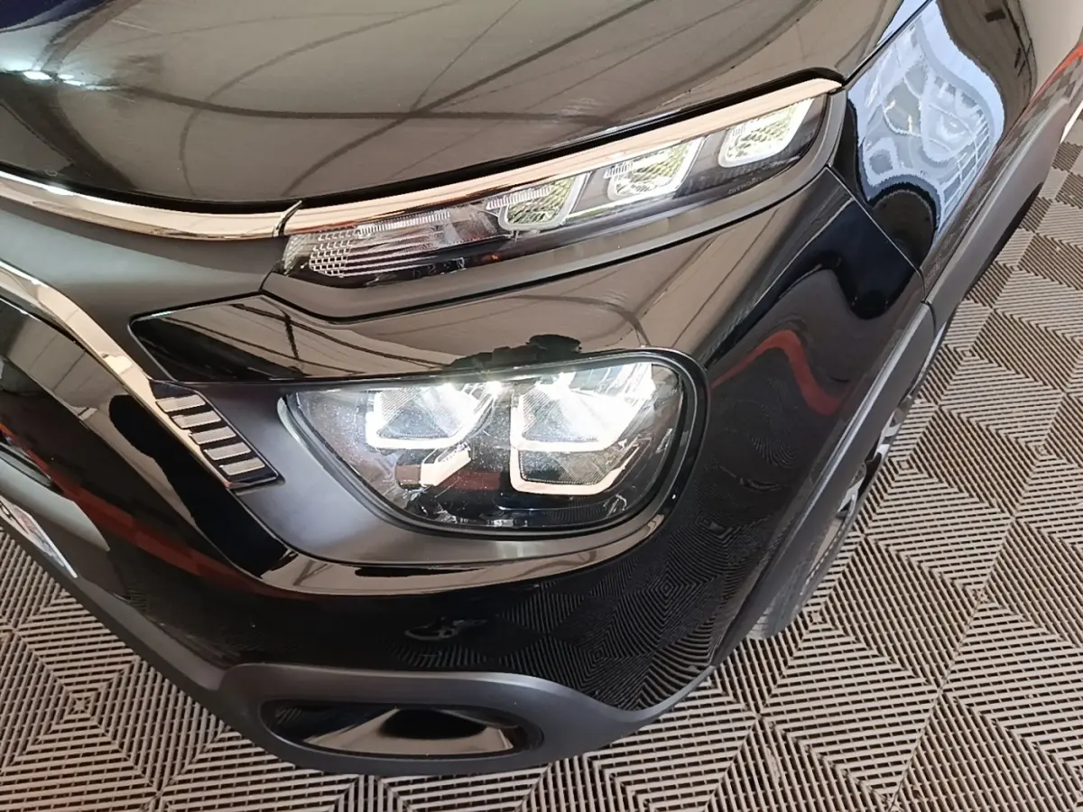 Gros plan sur le phare avant droit noir brillant de la Citroën C3 2022 avec feux LED et détails chromés.