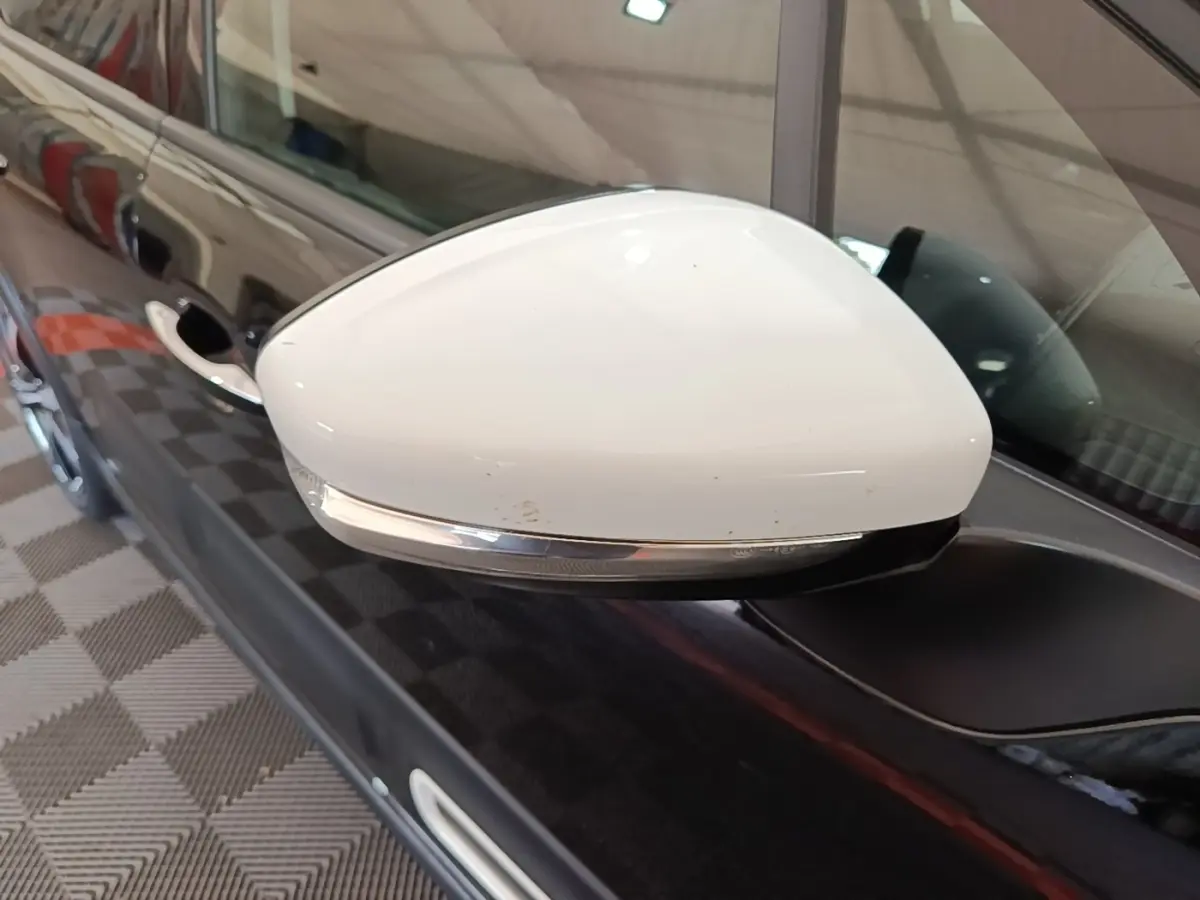 Gros plan sur le rétroviseur blanc côté gauche d'une Citroën C3 noire, avec clignotant intégré.