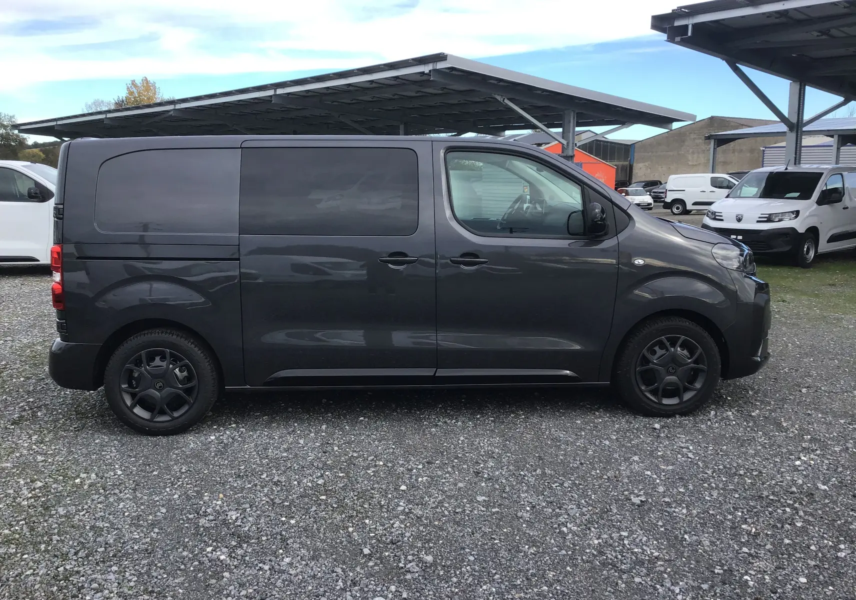 Profil côté gauche d'un Citroën Jumpy Cabine Approfondie gris titane, avec jantes noires et vitres teintées.
