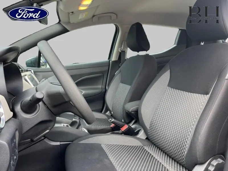 Vue intérieure côté conducteur d'une Nissan Micra gris acier 2022, sièges tissu bi-ton noir et gris avec surpiqûres.