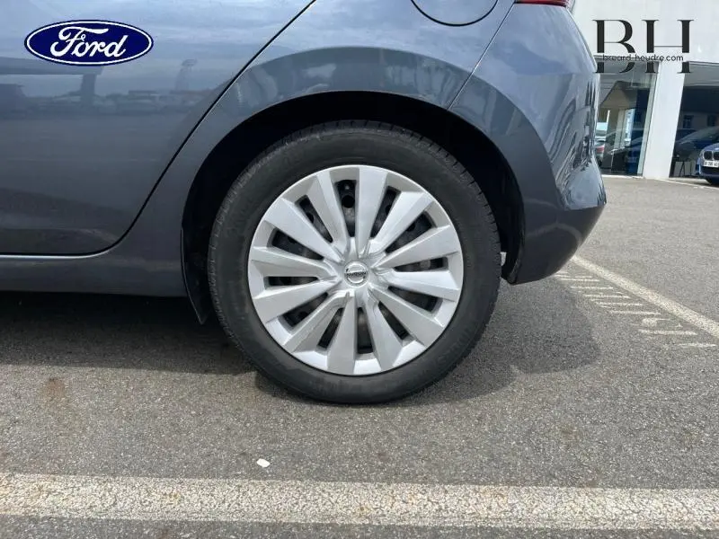 Gros plan sur la roue arrière droite d'une Nissan Micra gris acier avec enjoliveur à rayons visibles.