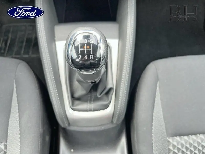 Le levier de vitesses manuel noir et chrome vu de dessus entre deux sièges gris foncé d'une Nissan Micra 2022