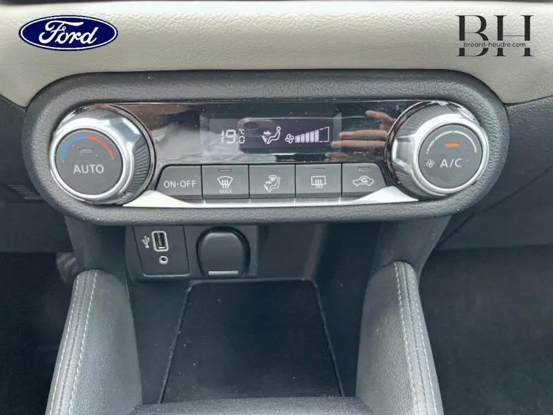 Gros plan sur la commande de climatisation automatique d'une Ford, avec écran digital et boutons rotatifs chromés.