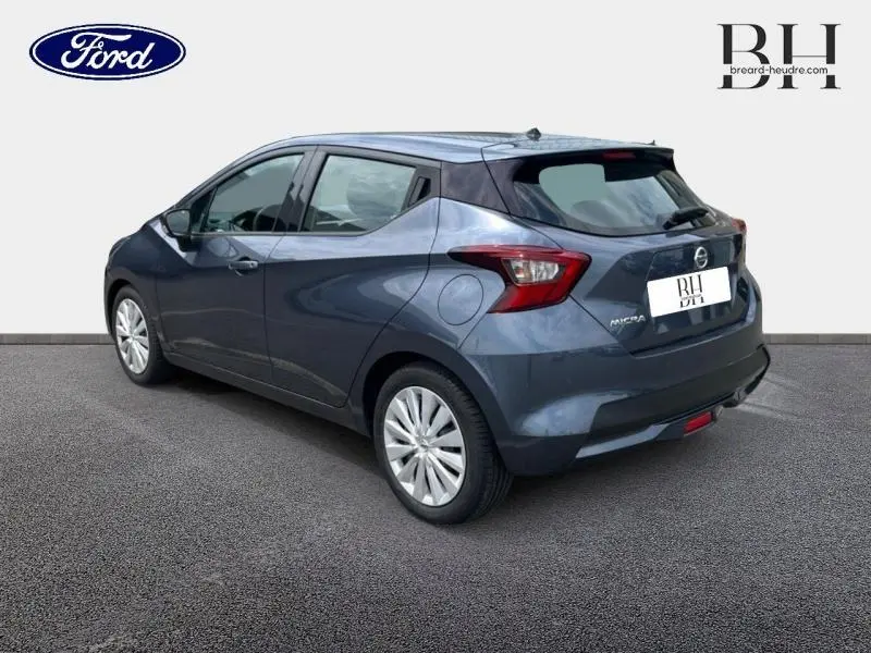 Nissan Micra gris acier vue 3/4 arrière droit, avec feux arrière caractéristiques et jantes argentées.