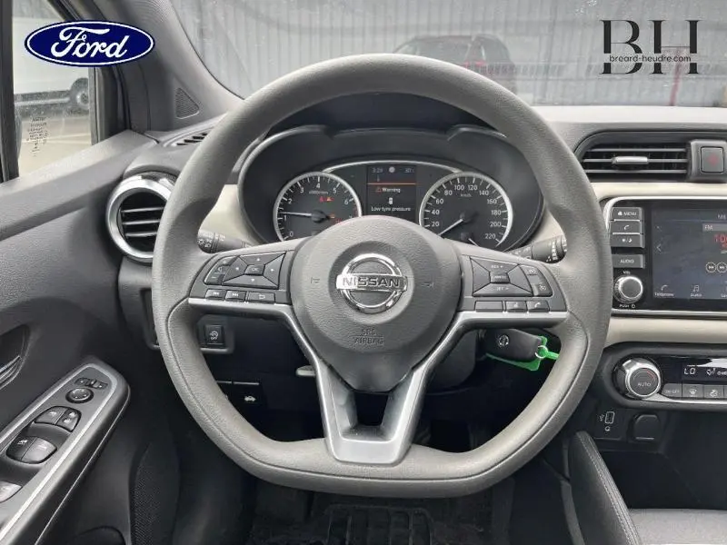 Vue intérieure centrée sur le volant multifonction d'une Nissan Micra gris acier avec tableau de bord et écran tactile.