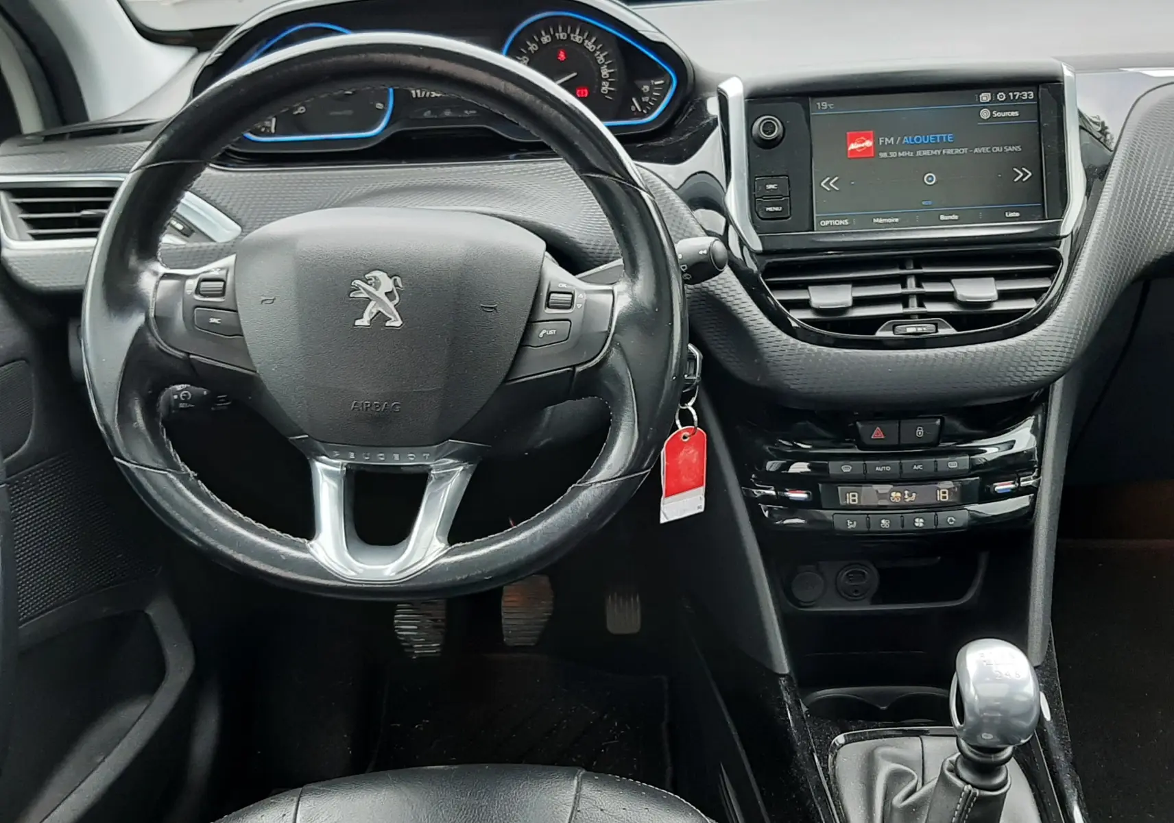 Vue intérieure du tableau de bord et volant cuir noir du Peugeot 2008 2017 avec écran tactile et levier de vitesses manuel.