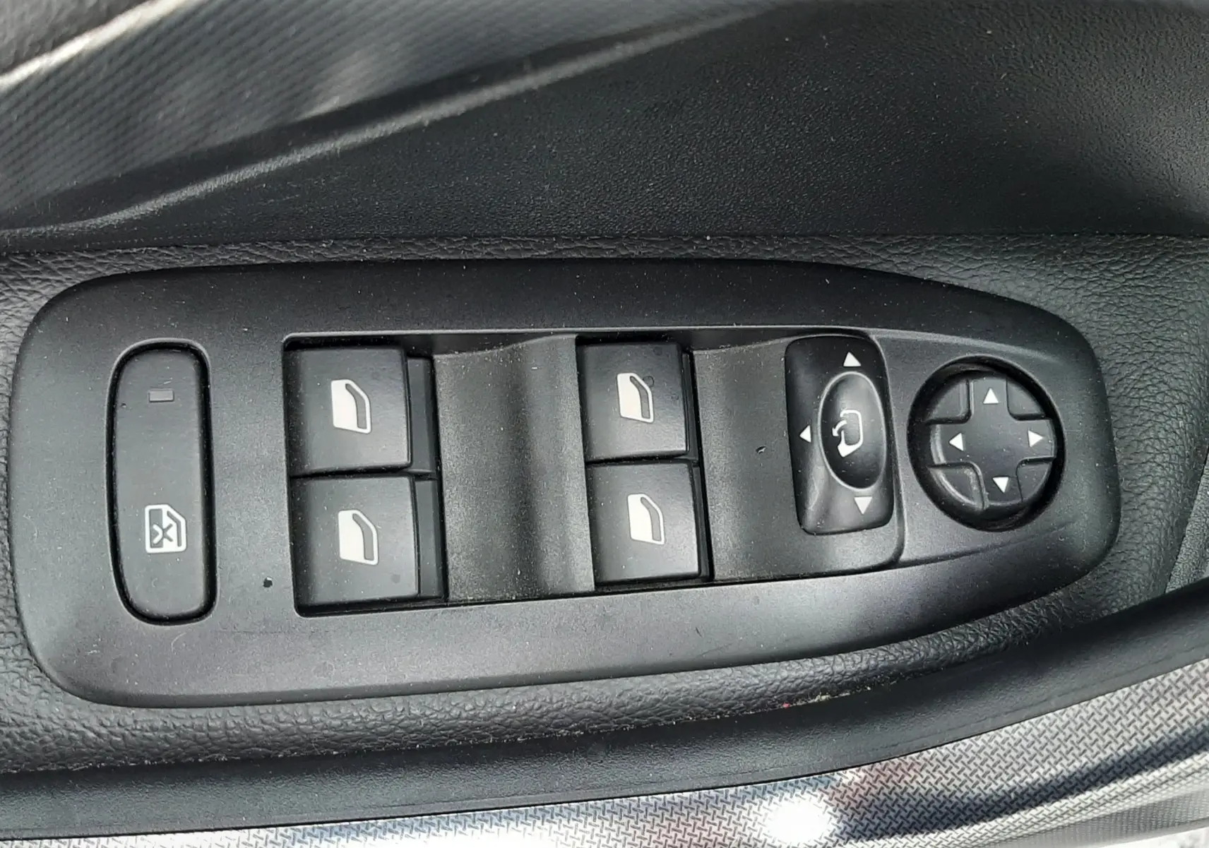 Gros plan sur les commandes des vitres et des rétroviseurs côté conducteur d'une Peugeot 2008 blanche de 2017.