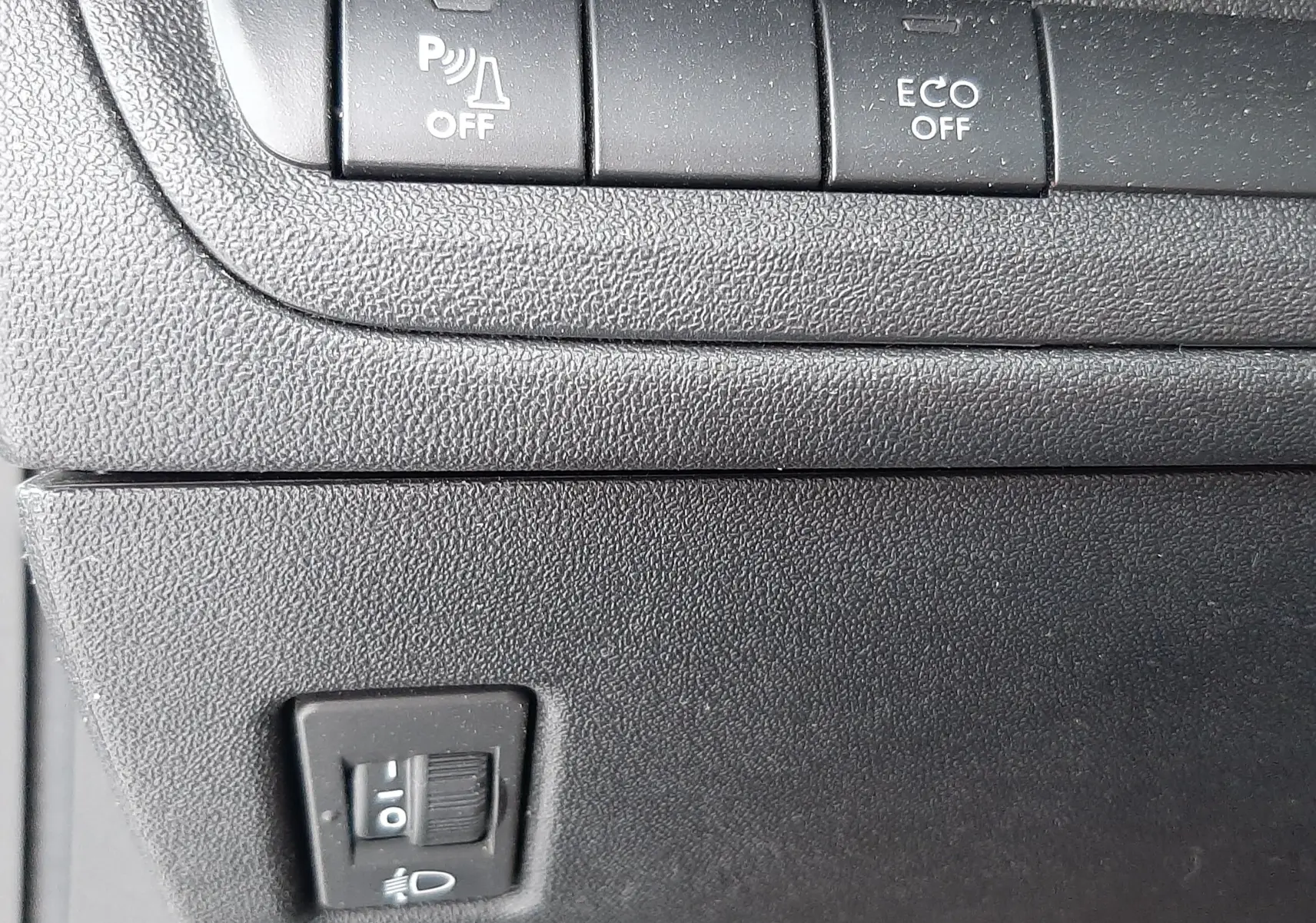 Gros plan sur les boutons de commande du tableau de bord noir du Peugeot 2008 blanc, avec fonction ECO et capteurs désactivés.