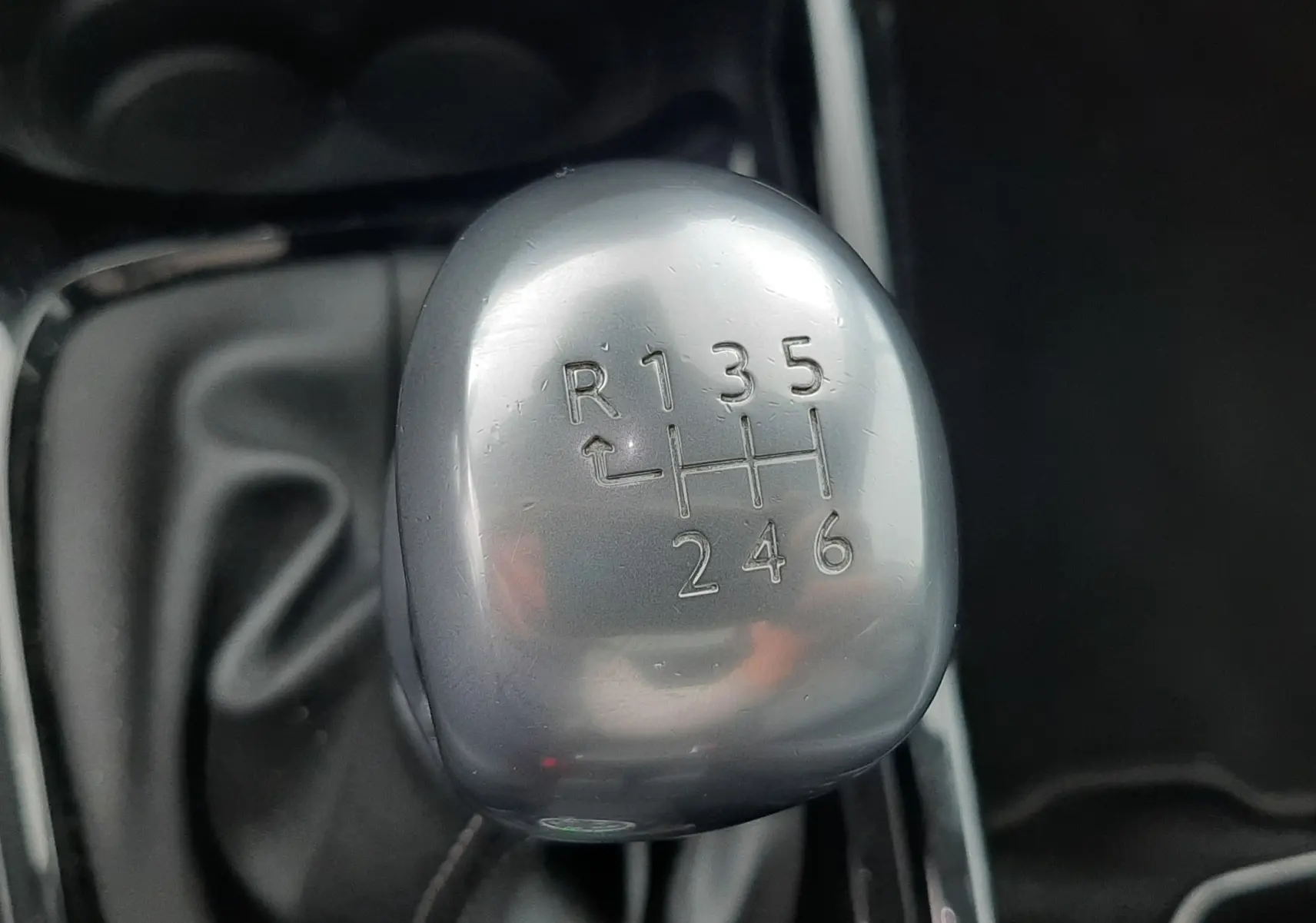 Gros plan sur le levier de vitesses manuel gris argenté du Peugeot 2008 blanc de 2017, montrant les six rapports et la marche arrière.