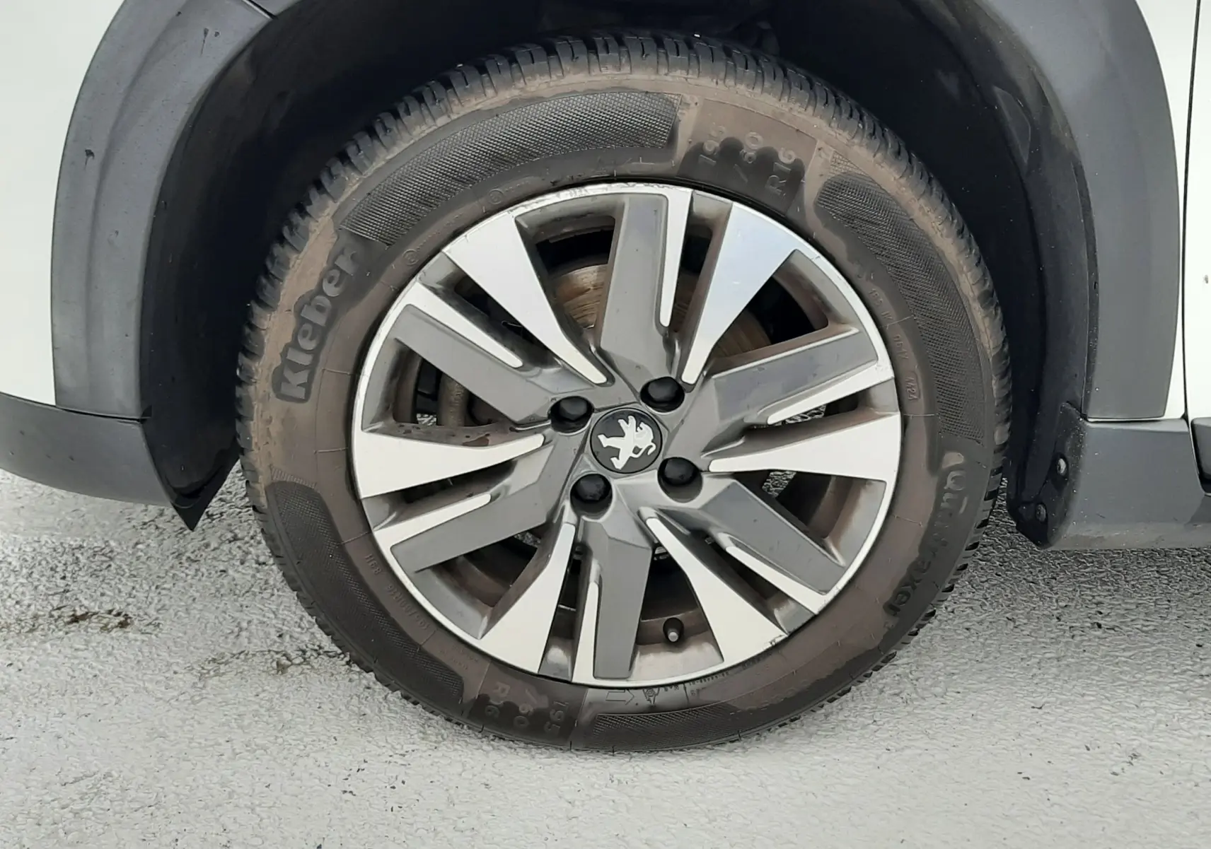 Gros plan sur la roue avant gauche d'un Peugeot 2008 blanc de 2017 avec jante alliage et logo lion central.