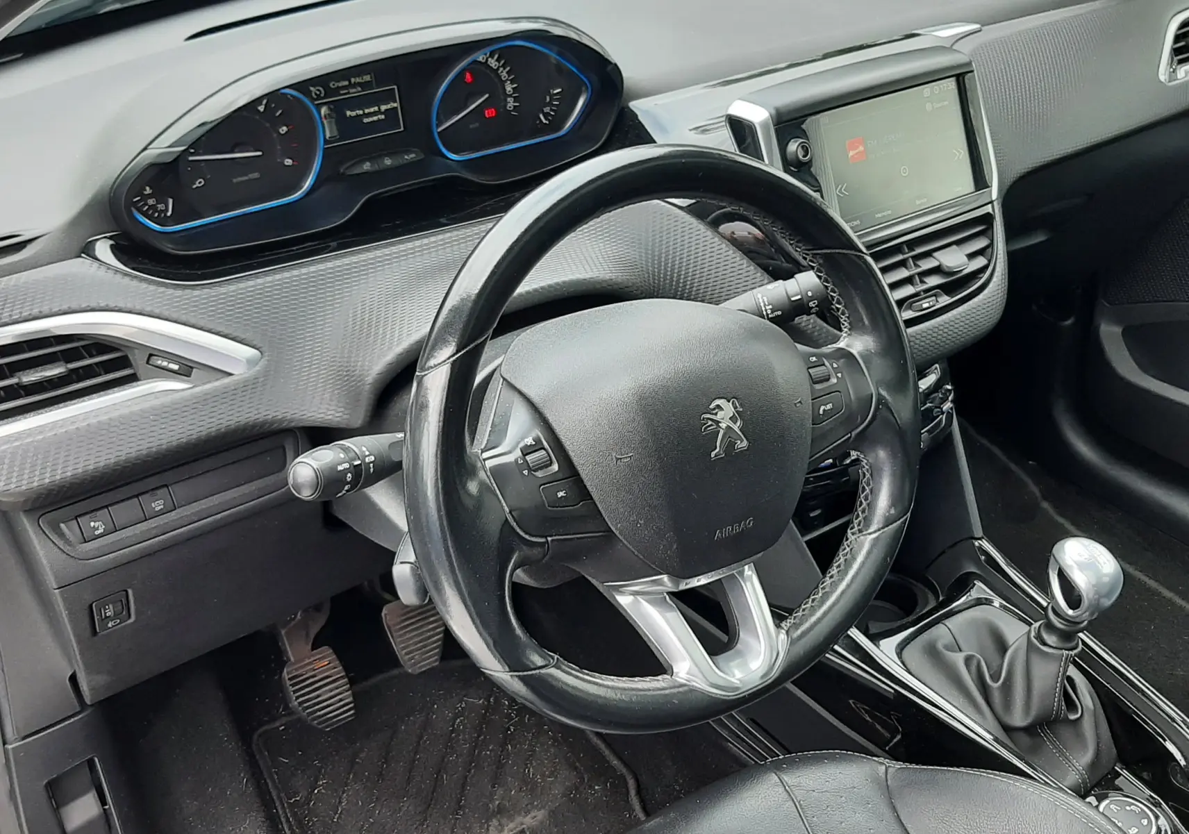 Intérieur noir du Peugeot 2008 2017, vue du poste de conduite avec volant cuir et levier de vitesse manuel.