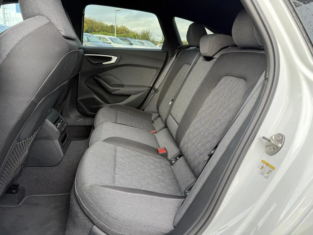 Vue côté droit des sièges arrière gris tissu de l'Audi A5 Avant blanc glacier métallisé 2025 avec porte ouverte.