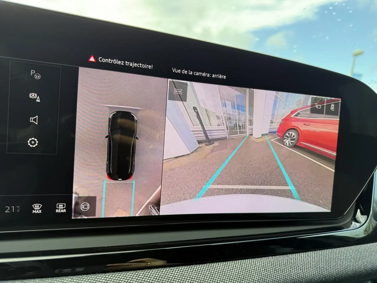 Vue de la caméra arrière sur l'écran du tableau de bord d'un Audi A5 blanc glacier, avec lignes de guidage bleues.