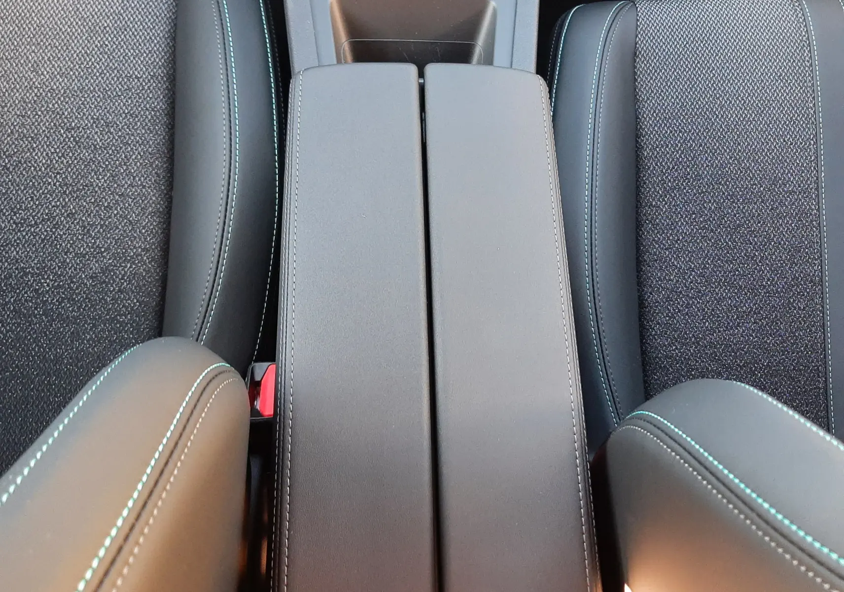 Vue plongeante sur la console centrale et les sièges noirs avec surpiqûres bleues de la Peugeot 308 Bleu Obsession 2025.