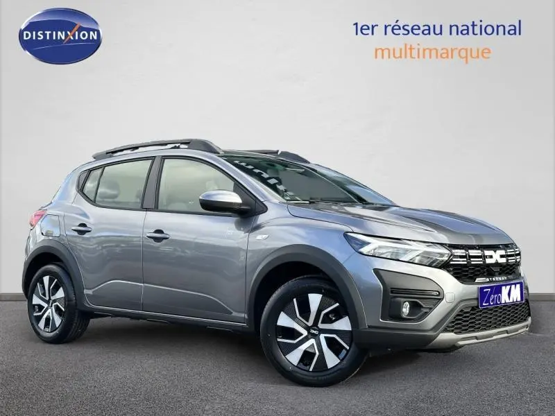 Vue 3/4 avant droite d'une Dacia Sandero Stepway grise avec jantes alliage et barres de toit noires