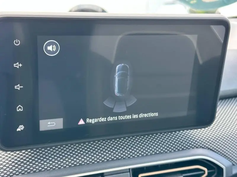 Écran tactile central du tableau de bord de la Dacia Sandero blanche montrant l'alerte de détection d'obstacles.