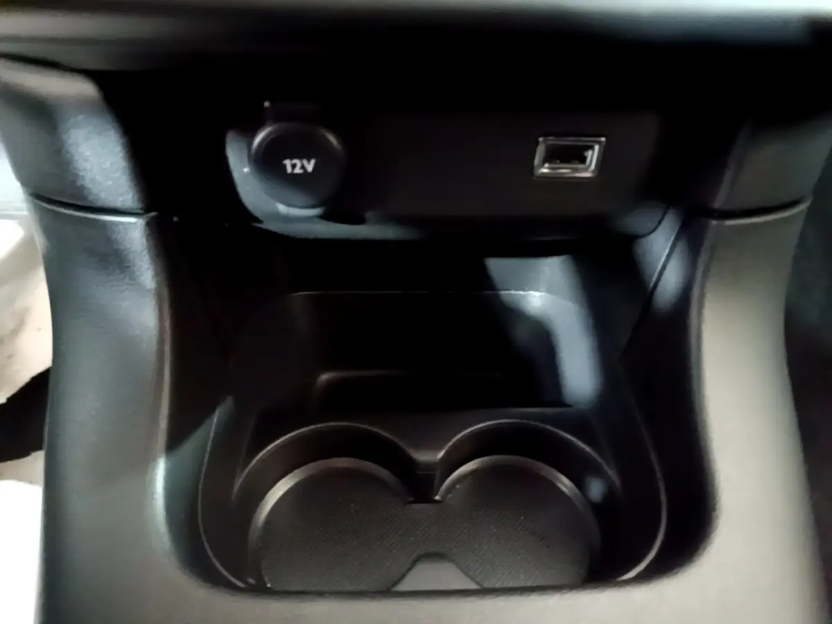 Gros plan sur la console centrale noire de la Citroën C3 Shine 2023, avec prise 12V et port USB visibles.