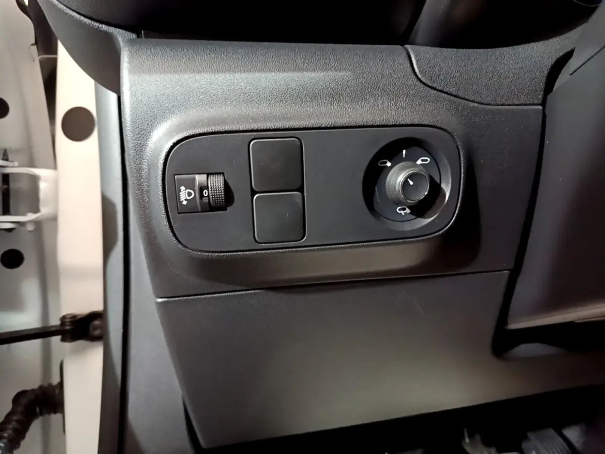 Vue rapprochée des commandes de réglage des phares et des rétroviseurs côté conducteur d'une Citroën C3 blanche 2023.