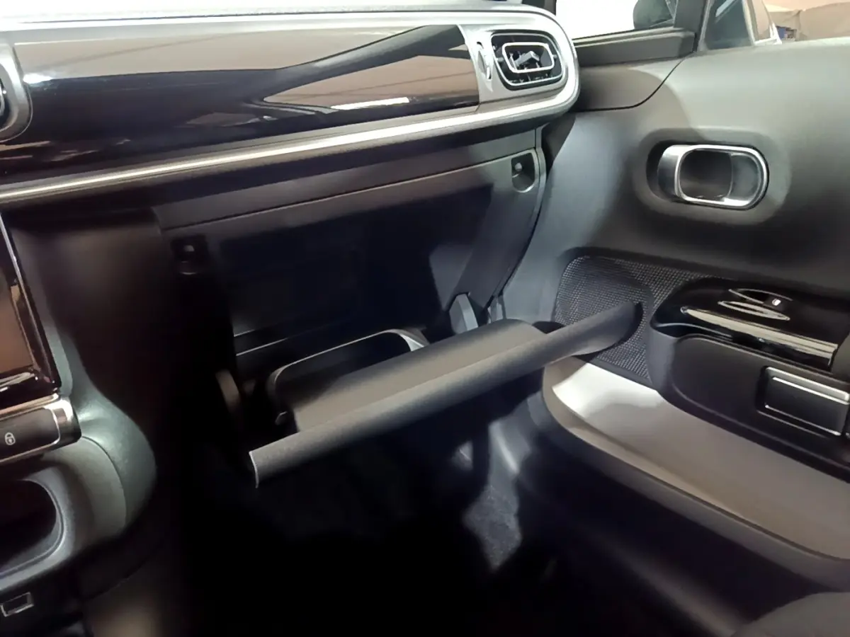 Intérieur côté passager de la Citroën C3 blanche 2023, avec boîte à gants ouverte et tableau de bord noir brillant.