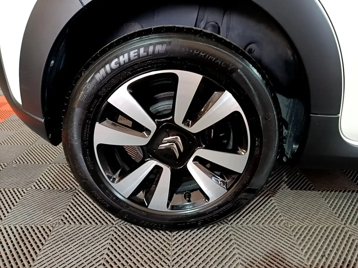 Gros plan sur la roue avant gauche d'une Citroën C3 blanche avec jante alliage bicolore et pneu Michelin.