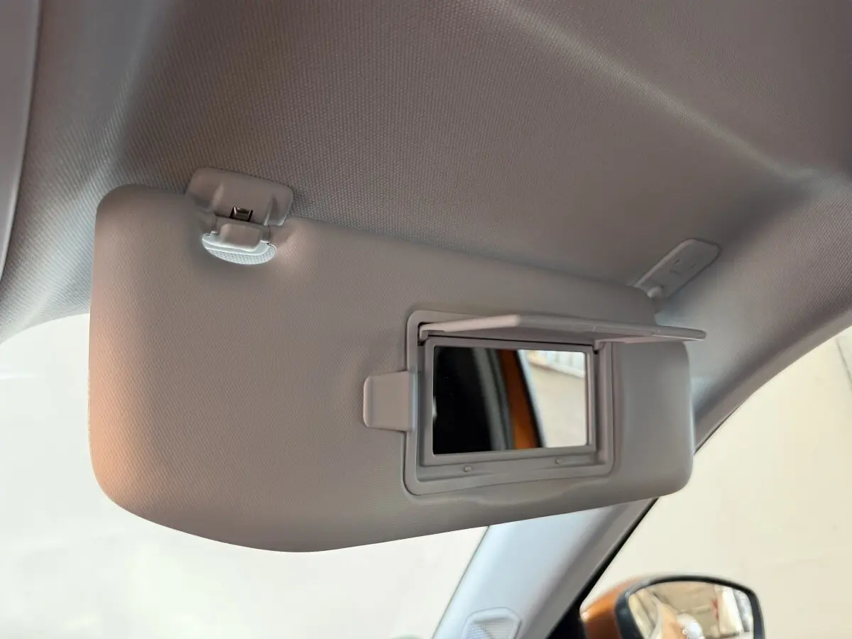 Détail intérieur montrant le pare-soleil gris avec miroir intégré côté conducteur d’un Peugeot 2008 orange.