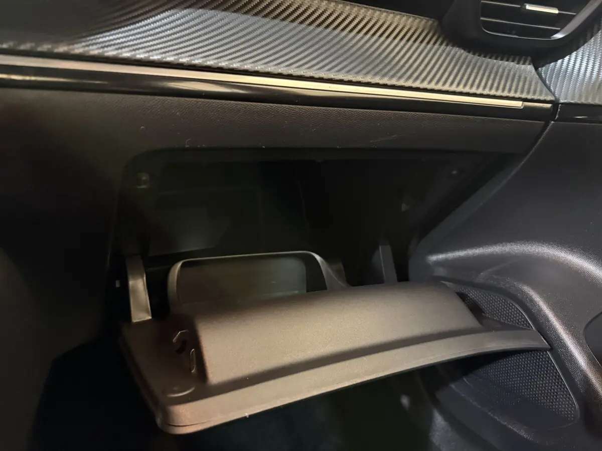 Gros plan sur la boîte à gants ouverte du Peugeot 2008 2022, intérieur noir avec finition effet carbone.