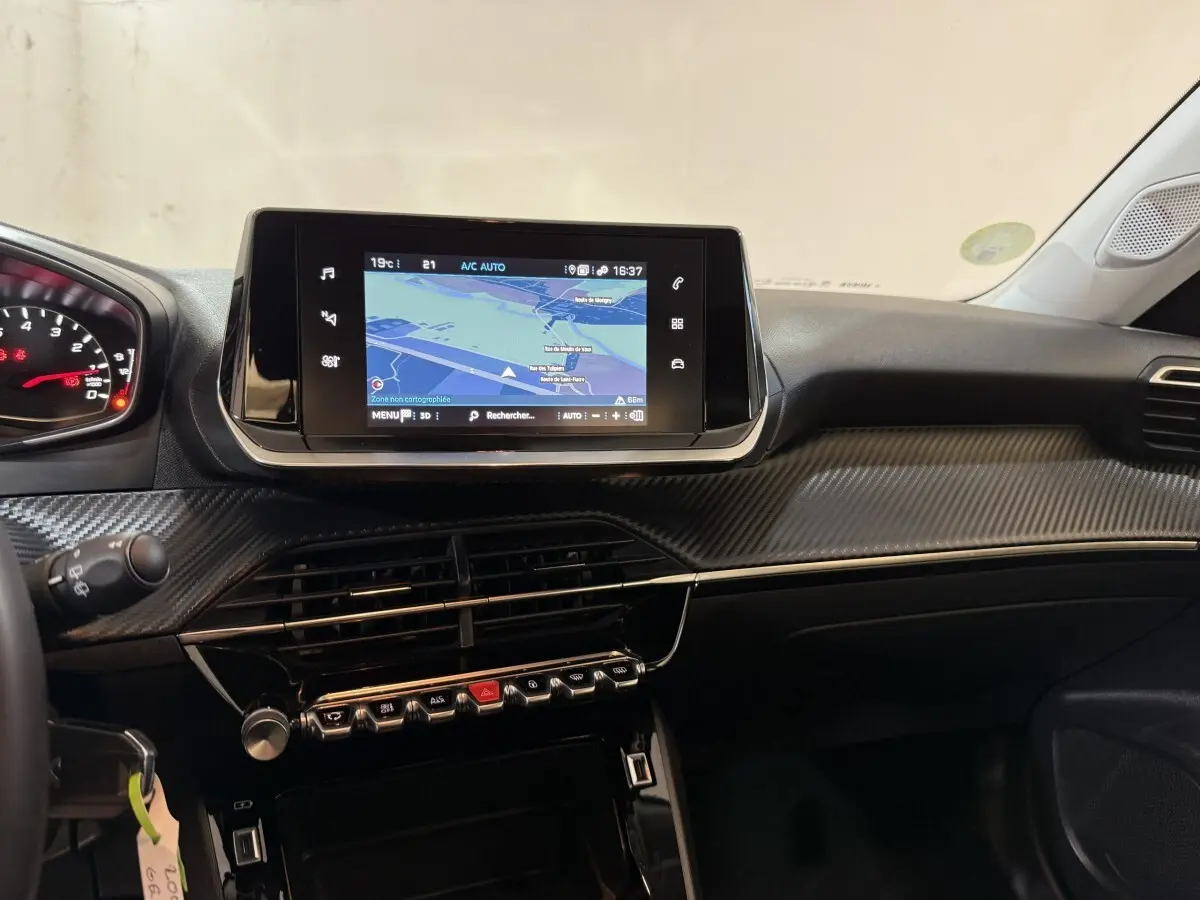 Vue intérieure du tableau de bord de la Peugeot 2008 orange, avec écran tactile de navigation et finition carbone.