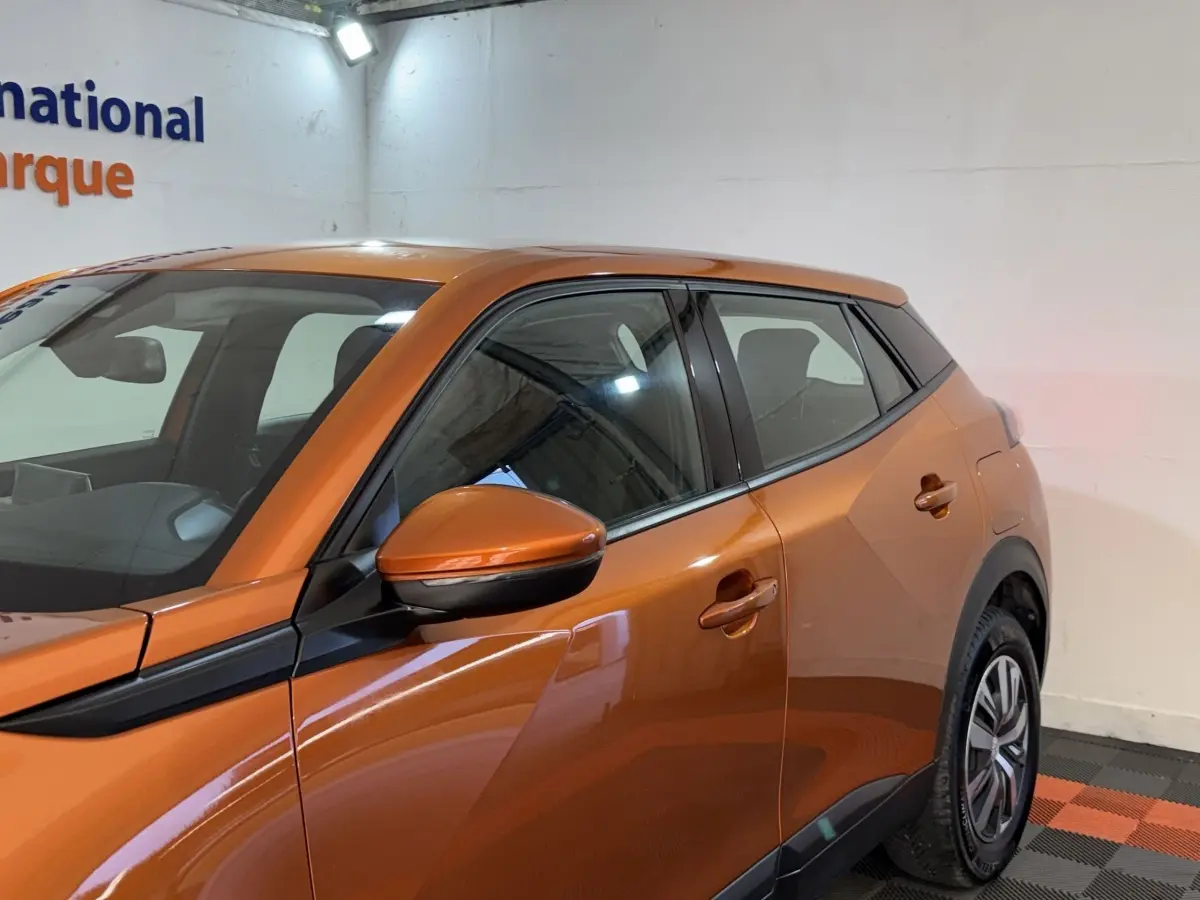 Vue de profil côté gauche d’un Peugeot 2008 orange 2022 avec rétroviseur et poignées assortis.