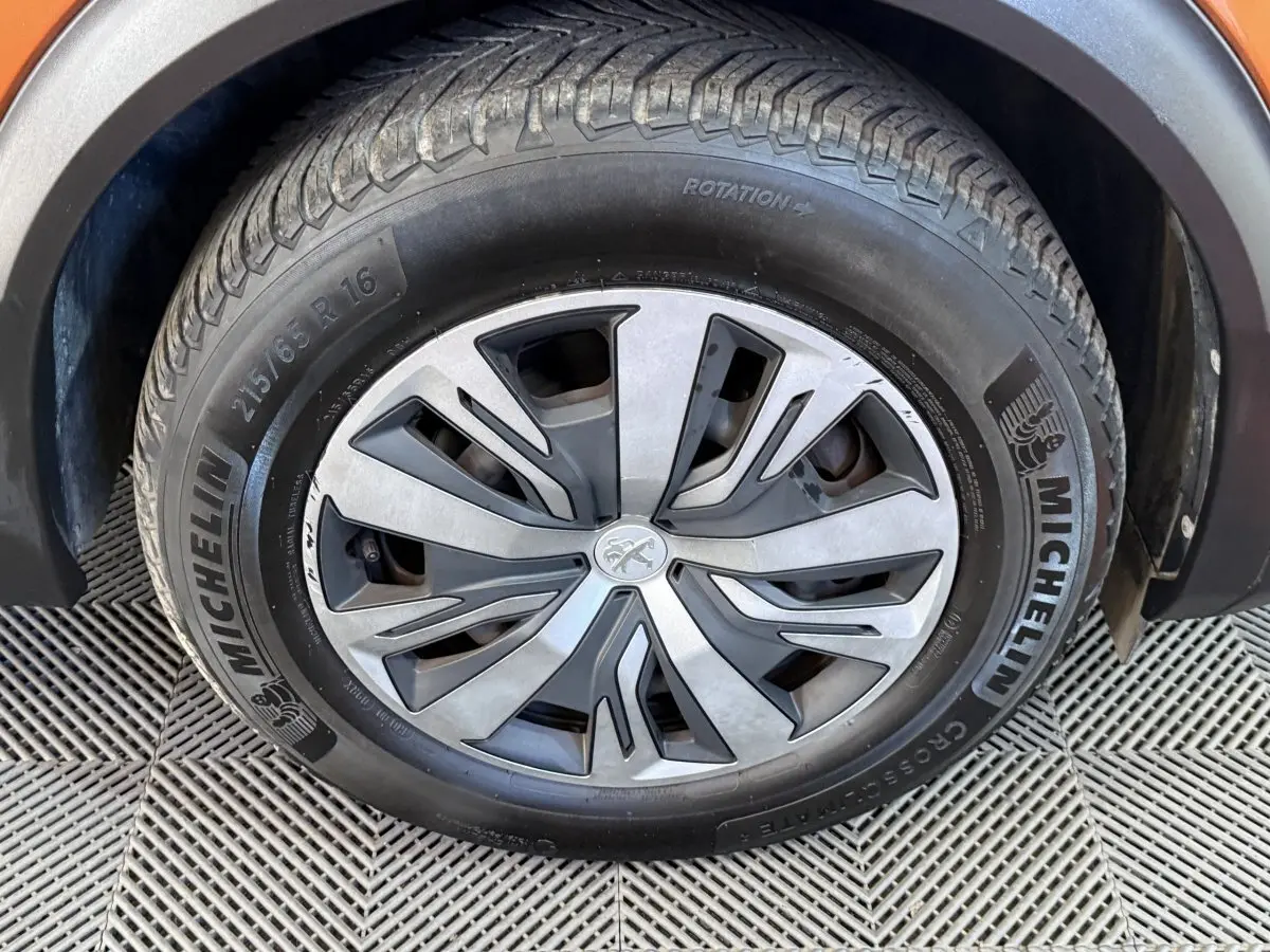 Gros plan sur la roue avant droite d’un Peugeot 2008 orange, avec jante alliage et pneu Michelin visible.