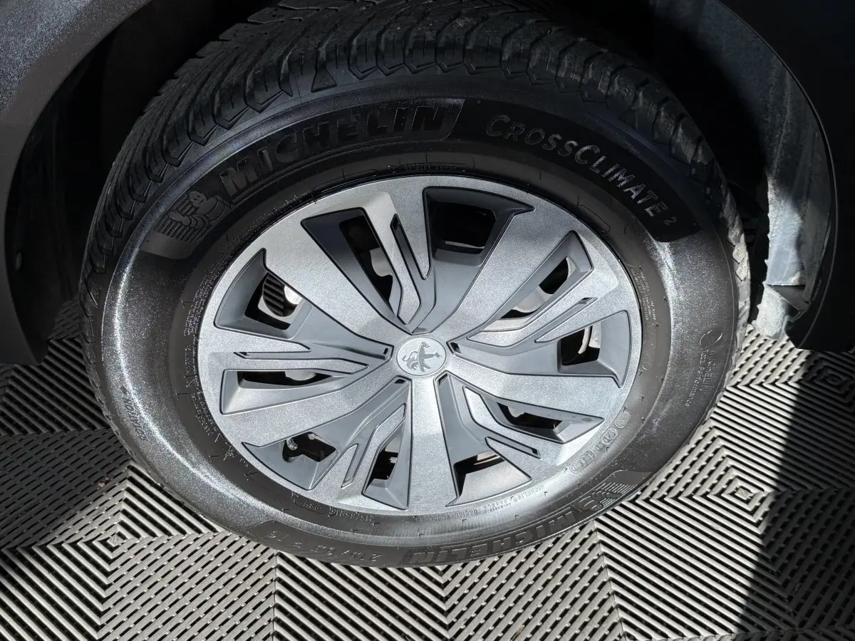 Gros plan sur la roue avant droite d’un Peugeot 2008 orange, mettant en valeur la jante aluminium et le pneu Michelin.