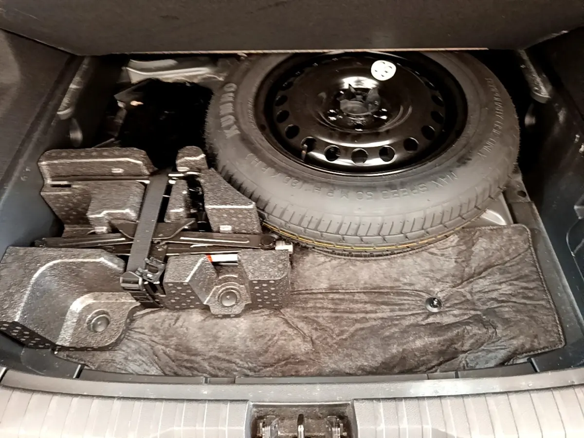 Coffre ouvert du Renault Arkana gris clair 2023 montrant la roue de secours et le kit de réparation sous le plancher.