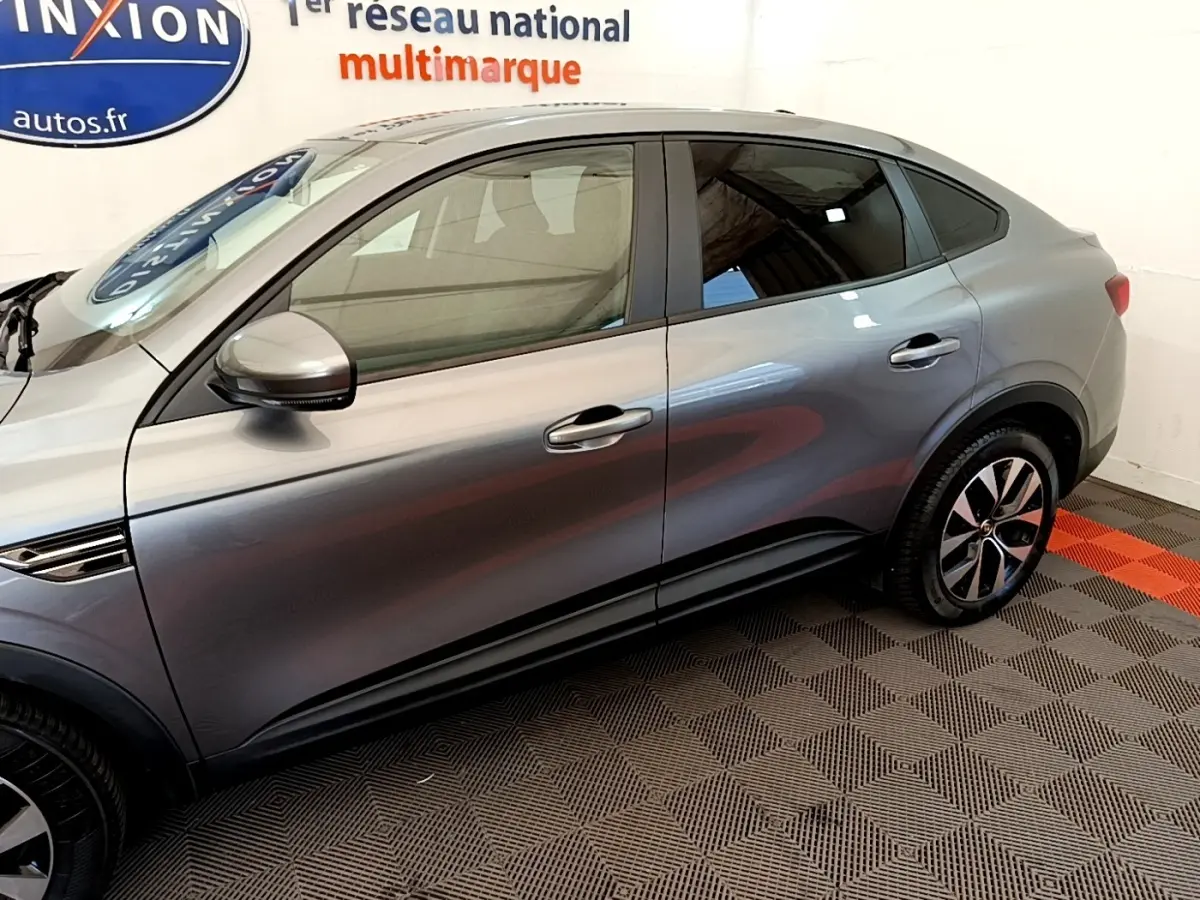 Vue latérale droite d'un Renault Arkana gris clair Evolution E-Tech hybride, soulignant ses jantes et lignes fluides.