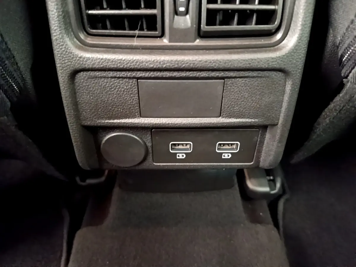 Vue rapprochée des ports USB doubles et prise 12V arrière dans l’habitacle noir du Renault Arkana gris clair.