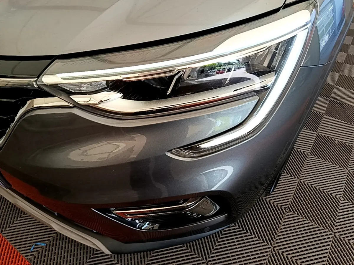 Gros plan sur le phare avant droit gris clair du Renault Arkana Evolution E-Tech 2023 avec détails LED et calandre brillante.