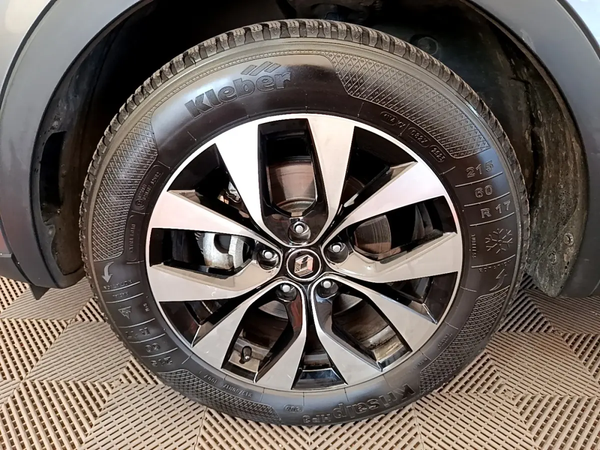 Gros plan sur la roue avant gauche du Renault Arkana gris clair, mettant en valeur la jante alliage bicolore et le pneu Kleber.