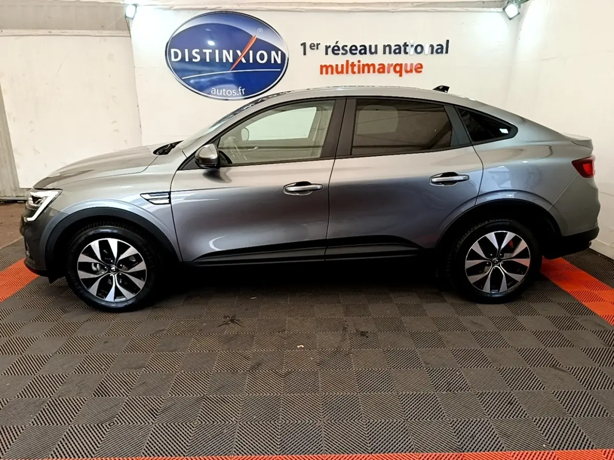 Profil droit d'une Renault Arkana gris clair 2023, avec jantes alliage et lignes fluides de SUV coupé.