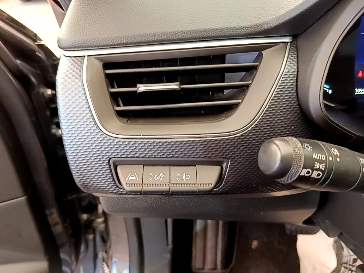Détail du tableau de bord gris clair côté gauche avec aérateur et commandes d'assistance sur Renault Arkana Evolution E-Tech 2023.