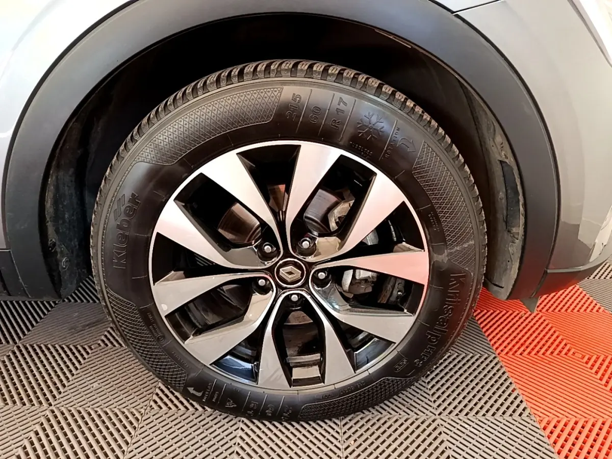 Gros plan sur la roue avant droite d’un Renault Arkana gris clair, jante alliage noir et argentée.