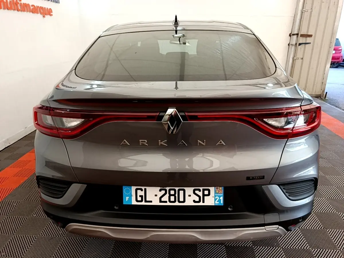 Vue arrière d’une Renault Arkana gris clair avec feux LED reliés et logo central bien visible.