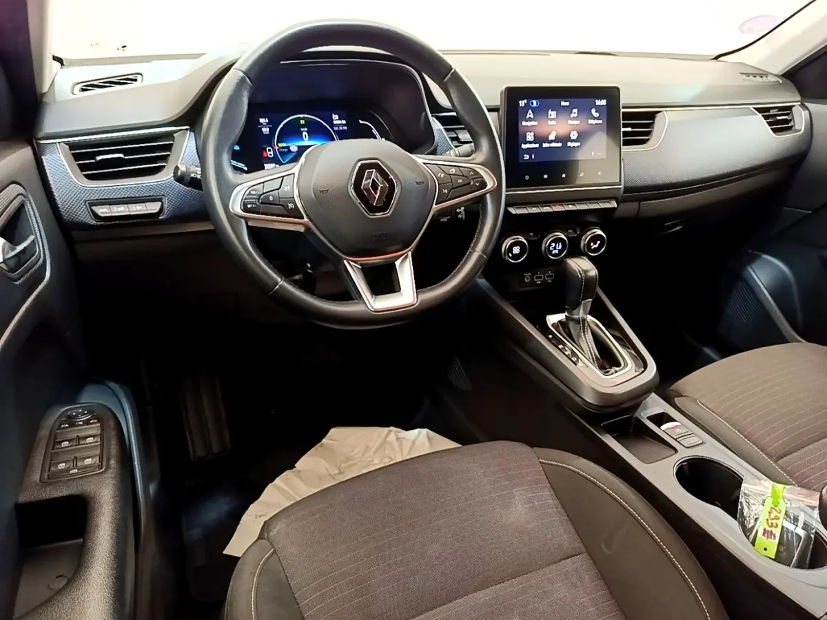 Vue intérieure de face du tableau de bord et volant noir du Renault Arkana Evolution E-Tech 2023 avec écran tactile central.