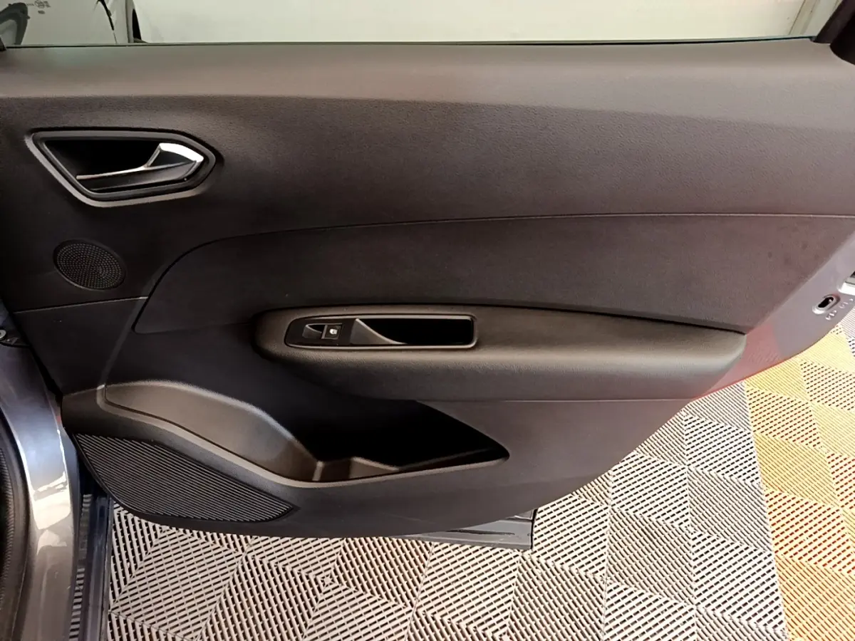 Vue intérieure de la porte côté gauche d'un Renault Arkana gris clair, avec poignée et commande de fenêtre noire.
