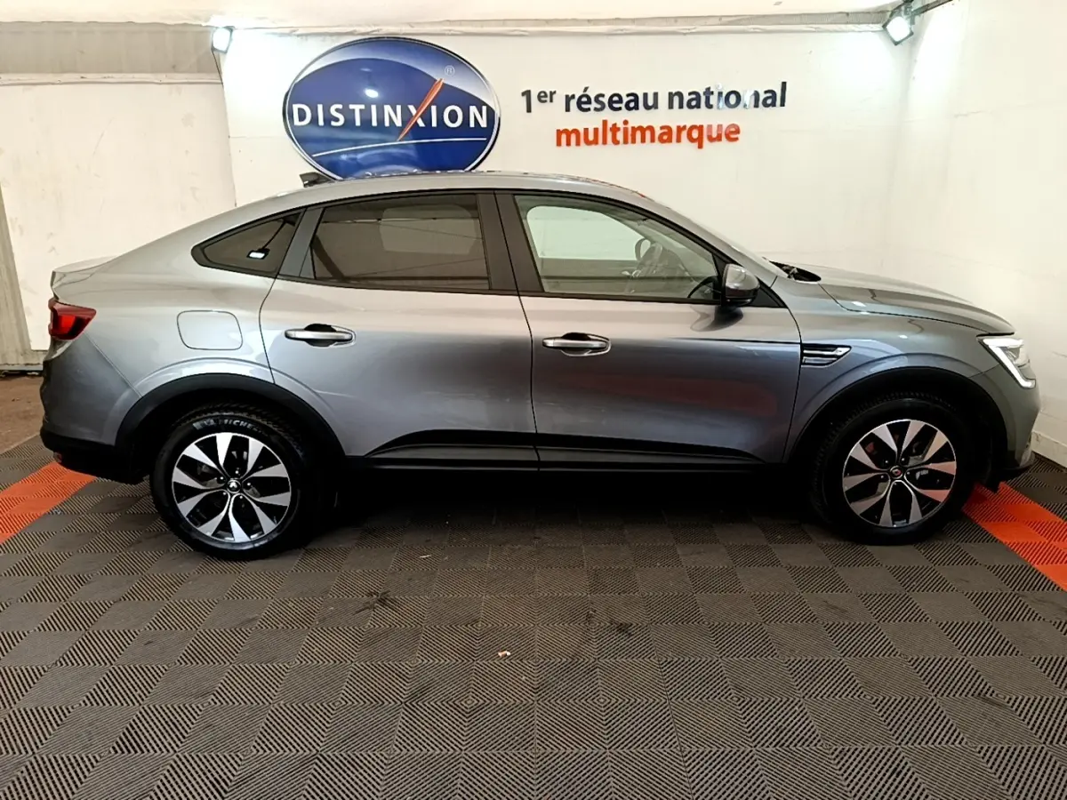 Profil droit d’un Renault Arkana gris clair 2023 Evolution E-Tech full hybrid, avec jantes alliage et lignes fluides.